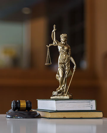 Gavel and Lady Justice statue on law books