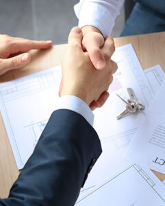 Two individuals shaking hands over legal documents on a table