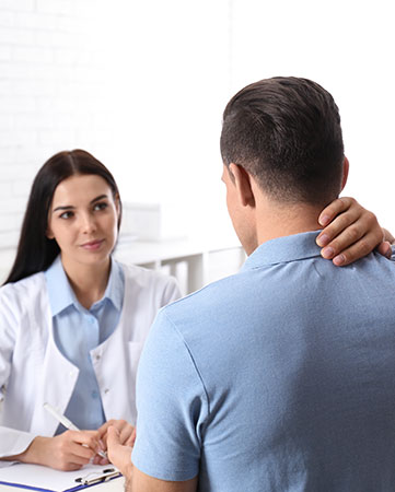 A man discussing his pain issue with a doctor at a desk.