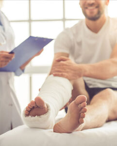 A man with a leg cast sits on a bed, indicating a personal injury.