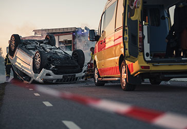 Image of a car overturned in the middle of a road.